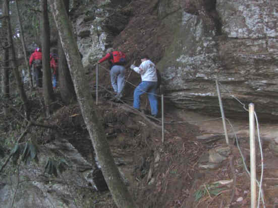 A narrow section of trail beside massive rock cliffs.