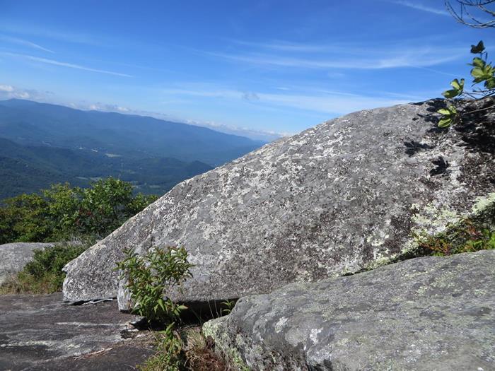 Huge boulders on top of the rock-faced mountain.