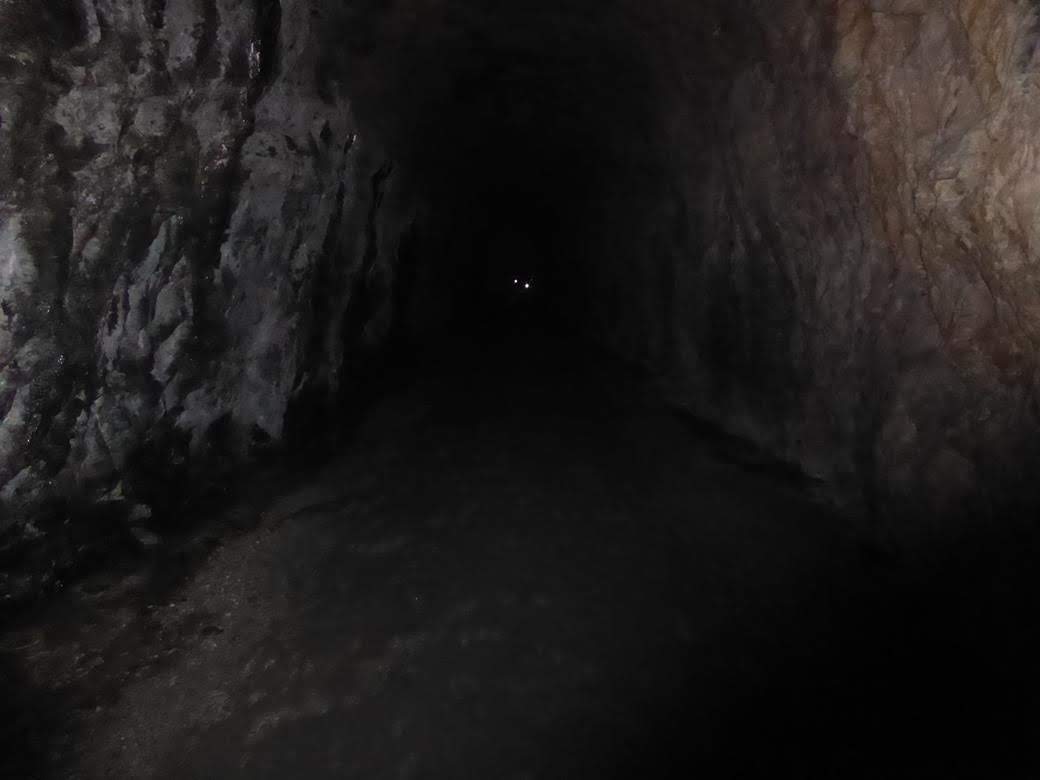 Walking into the tunnel we see people with flashlights in the distance.